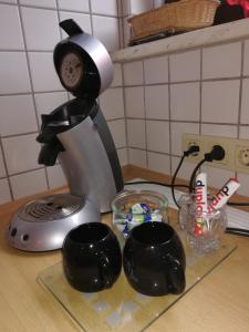 une cafetière et deux tasses noires sur un comptoir dans l'établissement Ferien- und Business Wohnung, à Mönsheim