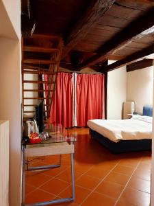 a bedroom with a bed and a table and red curtains at Piccolo Hotel Olina in Orta San Giulio
