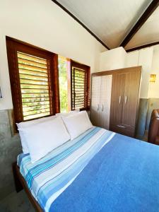 1 dormitorio con 1 cama con sábanas azules y almohadas blancas en Santo Hostel, en Porto Seguro