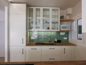 a kitchen with white cabinets and a sink at Apartament a Palamós amb plaça de parking in Palamós +21 photos
