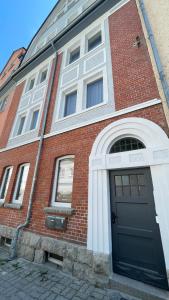 a red brick building with a black door on it at Hygge-Apartment Jena in Jena