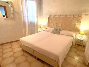 una camera da letto con un grande letto bianco con due lampade di Villa La Rosa dei Venti a Codaruina