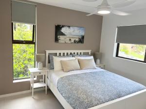 a white bedroom with a bed and two windows at NEW - Sunny Coolum Beach Retreat in Coolum Beach