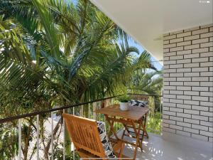 a balcony with a table and chairs and palm trees at NEW - Sunny Coolum Beach Retreat in Coolum Beach