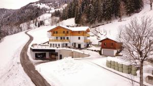 a house on a snow covered hill with a road at Sonnseit Appartement in Sankt Veit im Pongau