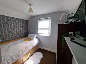 a small bedroom with a bed and a window at The Griffen Lodge in Plumstead