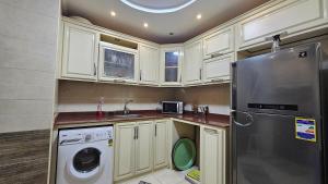 a kitchen with white cabinets and a washer and dryer at Welcome sea view - families only in Alexandria