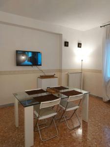 a dining room table with chairs and a television on the wall at Appartamento Levante in Bari