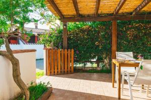 eine Terrasse mit einer hölzernen Pergola sowie einem Tisch und Stühlen in der Unterkunft Case Vacanze Il Sogno 2 in Porto Pino