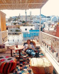 a woman sitting on a balcony with a coffee table at The Riad Hostel Tangier in Tangier