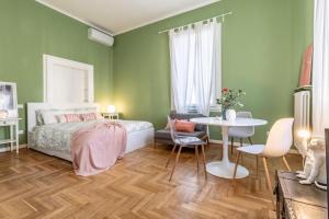 a bedroom with green walls and a bed and a table at Studio liberty a 100 metri dalle mura in Bassano del Grappa