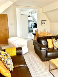 a living room with a leather couch and a kitchen at Holland House in New Brighton