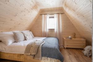 een slaapkamer met een bed met een houten muur bij Leśna Chatka in Dzianisz