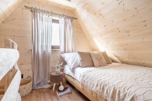 a bed in a wooden room with a window at Leśna Chatka in Dzianisz