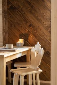 een houten tafel met een stoel en een houten muur bij Leśna Chatka in Dzianisz