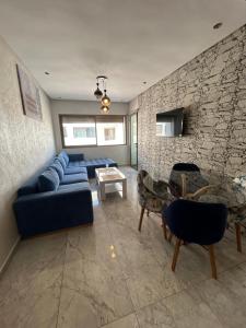 a living room with a blue couch and a stone wall at Appartement moderne à louer in Mansouria
