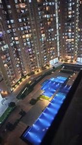 SOLACE Premium 2BHK Apartment near Manyata Tech Park And Hebbal في بانغالور: اطلالة على مبنى كبير مع مسبح في الليل