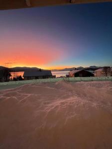 Un campo di neve con un fienile al tramonto di Apartment with a unique view, center of Kvaløya a Tromsø