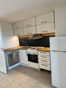 een keuken met witte kasten, een fornuis en een koelkast bij Apartment with a unique view, center of Kvaløya in Tromsø