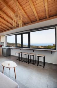 Monopati Eco Villas في Raches: غرفة معيشة مع طاولات وكراسي ونوافذ