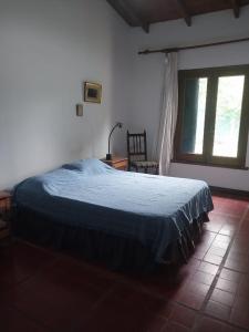 ein Schlafzimmer mit einem Bett mit einer blauen Decke und einem Fenster in der Unterkunft Casa Quinta El Cultivo in San Antonio de Areco