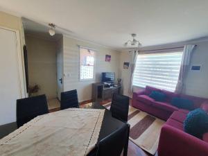 uma sala de estar com uma mesa e um sofá roxo em Cómoda casa con estacionamiento privado em Villarrica