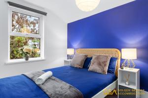 a blue bedroom with a bed and a window at Stylist and Cosy 3 Bed House Sleeps 7 Free Parking in London