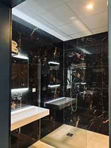 een zwarte badkamer met een wastafel en een spiegel bij Firstclass Event & Hotel in Fürth