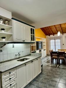 a kitchen with white cabinets and a dining room at Casa con pileta cerca del Parque in Godoy Cruz