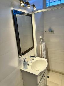 a white bathroom with a sink and a mirror at Casa con pileta cerca del Parque in Godoy Cruz