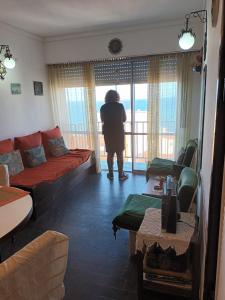 una persona parada en una sala de estar mirando por la ventana en Mardel super vistas del mar Torreon estar y 1 dorm 4 pax en Mar del Plata
