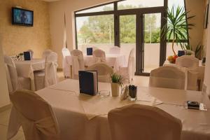 Habitación con mesas y sillas blancas y ventana grande. en Hotel Dijana en Pirot