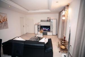 uma sala de estar com um sofá preto e uma televisão em JQ Apartments Prime em Acra