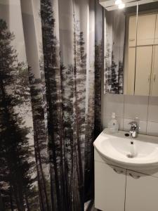 baño con lavabo y cortina de ducha con árboles en Hilla Apartments en Rovaniemi