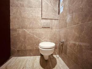 a bathroom with a toilet and a tiled wall at Wooib Hotels, Haridwar in Haridwār