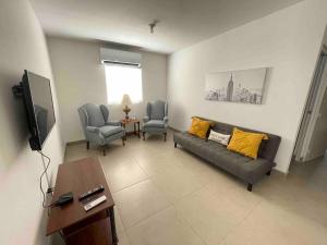 ein Wohnzimmer mit einem Sofa und 2 Stühlen in der Unterkunft Gabby’s Accesible House in Private area in Mexicali