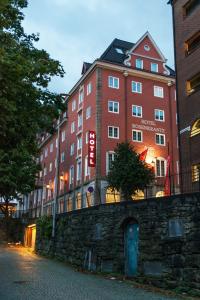 a large red building is next to a stone wall at Thon Hotel Rosenkrantz Bergen in Bergen