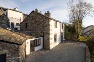 an external view of a stone house with a driveway at New 4 Bedroom Home at Waterhead Range by LetMeStay in Ambleside