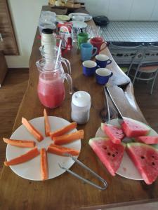 una mesa con platos de zanahorias, sandía y zumo en Aconchego Do Lar, en Campos do Jordão