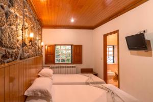 a bedroom with two beds and a tv on the wall at Casinhas das Tílias in Seia