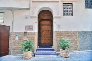 a building with a wooden door and two potted plants at Riad Alassala Fes in Fès