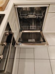 an empty dishwasher in a kitchen with its door open at Magnolia Palazzo in London