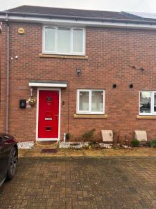 uma casa de tijolos vermelhos com uma porta vermelha em Soweway Coventry em Coventry