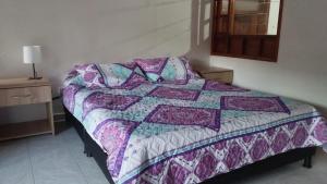 Una cama con edredón en una habitación en Mammamia CasaHotel, en Duitama