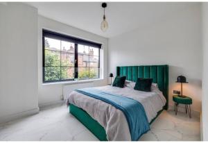 a bedroom with a bed with a green headboard and a window at Luxury Apartment: city centre, stylish, modern in Chester