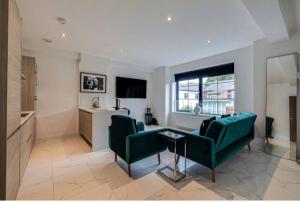 a living room with two green chairs and a kitchen at Luxury Apartment: city centre, stylish, modern in Chester