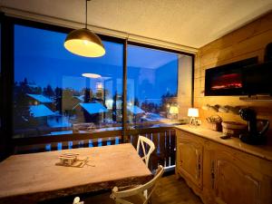 a dining room with a table and a large window at La joue du loup, aux pieds des pistes et vue sur montagnes in La Joue du Loup