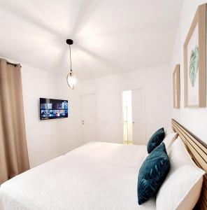 1 dormitorio con 1 cama blanca y TV en la pared en BuenaVista Gigantes Marina - Room with Private Bathroom en Acantilado de los Gigantes
