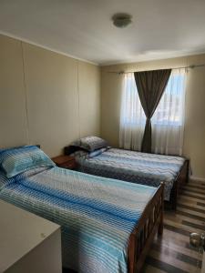 Duas camas num quarto com uma janela em Cómoda casa con estacionamiento privado em Villarrica