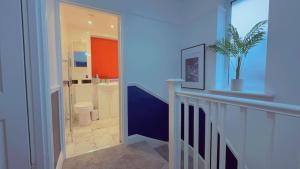 a bathroom with a hallway with a toilet and a plant at Cozy Room in London in Plumstead